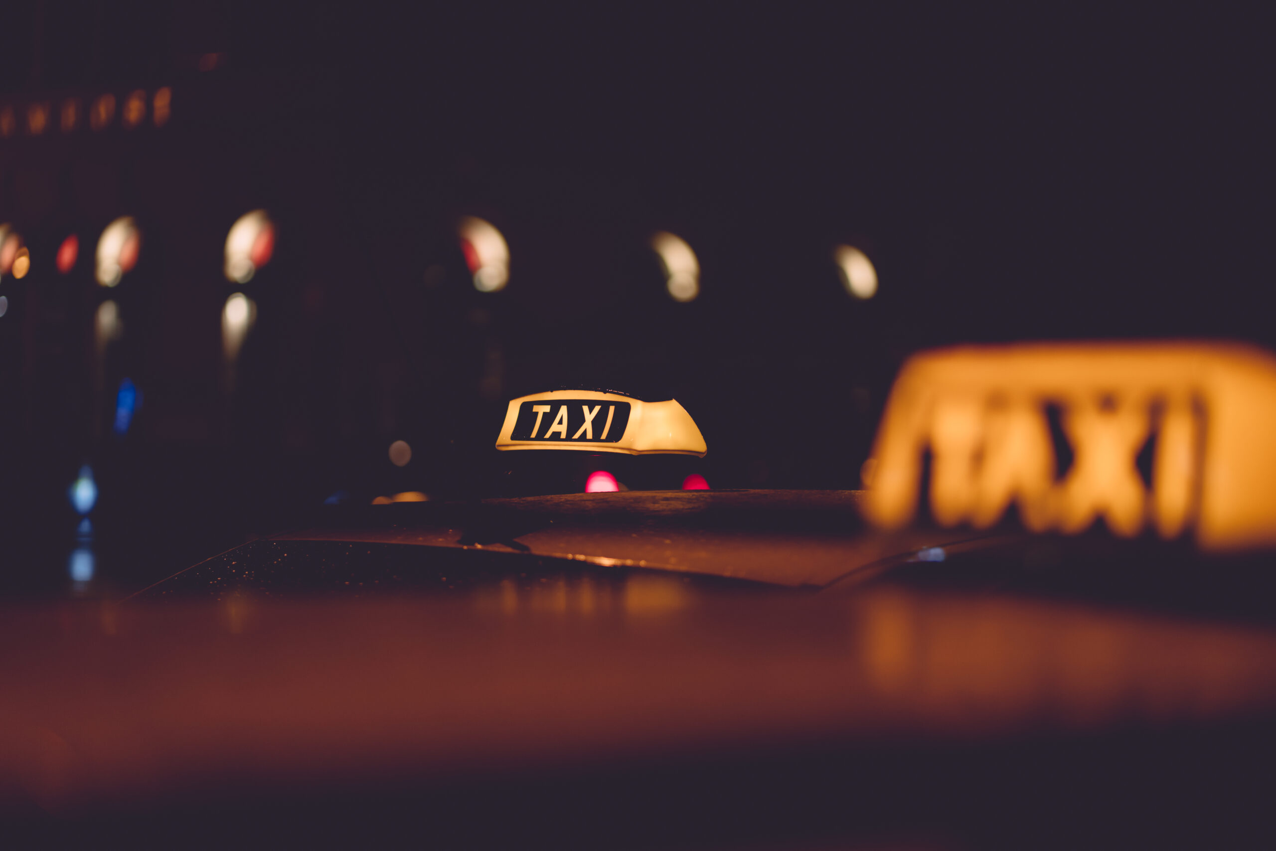 Gece şehir ışıkları arasında sarı taksi tabelası – Denizli Taksibul gece ulaşım hizmeti.